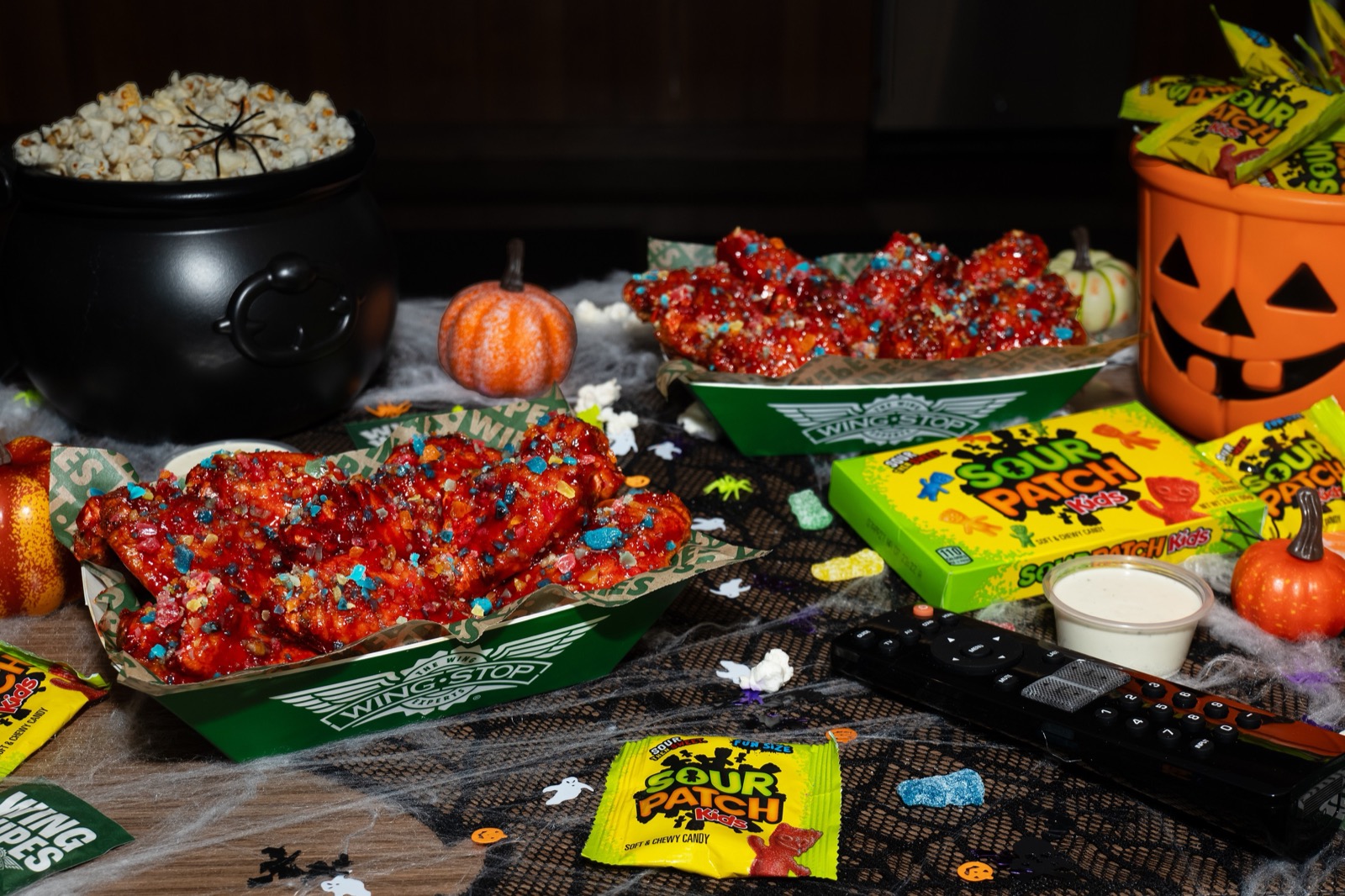 Wingstop wings with a red glaze and SOUR PATCH KIDS candy pieces next to SOUR PATCH KIDS candy and Halloween decorations